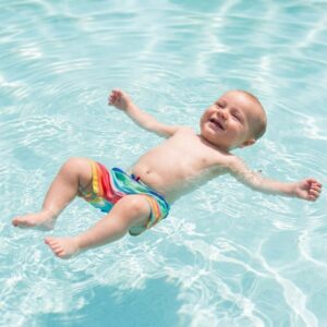 A young child with a bright smile confidently demonstrating a safe survival float on their back in clear blue water.